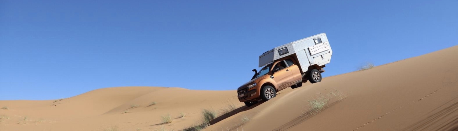 Expeditonsfahrzeug PickUpBack.com Ford Ranger fährt eine Düne in der Wüste herunter
